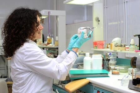 Dental technician checks his work in the labの写真素材