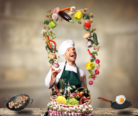Chef juggling with vegetables and other food in the kitchenの写真素材