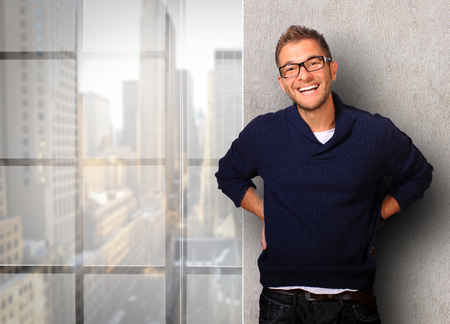 Young man in a blue sweater and jeans smilesの写真素材