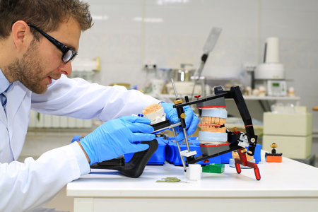 Dental technician checks his work in the labの写真素材