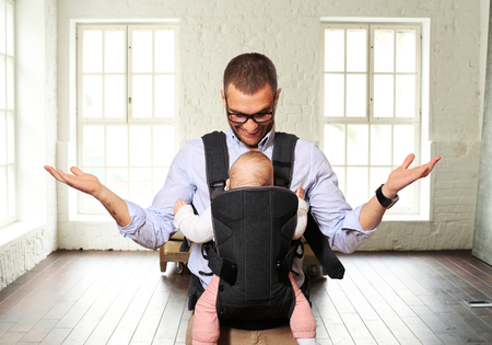 Father holds a baby in a bagの写真素材