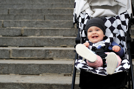 Cute baby in a hat sitting in a baby carriageの写真素材