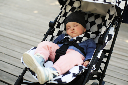 Cute baby in a hat asleep in a baby carriageの写真素材