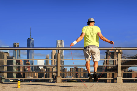 Morning exercises with skipping rope on the background of the cityの写真素材