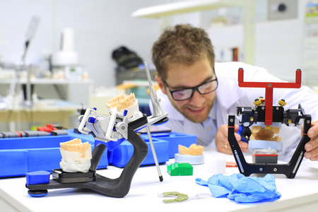 Dental technician checks his work in the labの写真素材