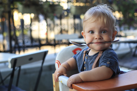 Little boy is sitting in a cafe with a spoonの写真素材