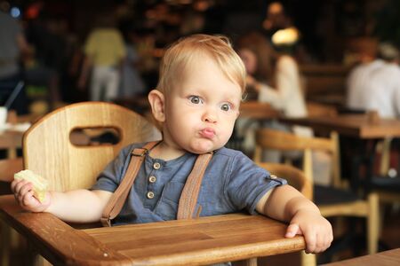 Little boy is sitting in a cafe with a bananaの写真素材