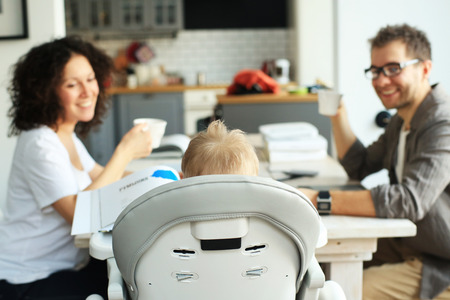 A little boy sits in a child seat with his parentsの写真素材