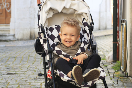 Little beautiful boy in a stroller on the streetの写真素材