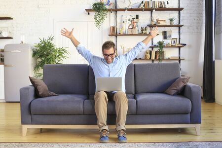 Young man sitting and working on sofa with laptop, business conceptの写真素材
