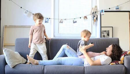 Mother and little sons are playing on the sofaの写真素材