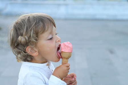 Little cute boy eating strawberry ice cream