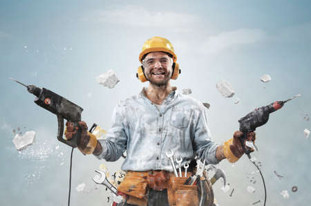 Construction worker in dirty clothes with a hammer and drill at workの写真素材