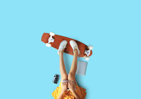 Young woman with a photo camera and a skateboard relaxes and restsの写真素材