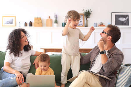Young beautiful happy family relaxing on the sofa and look at the laptop at home.