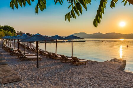 Nikiana beach with chairs and umbrellas at sunset time, Lefkada island, Greeceの写真素材