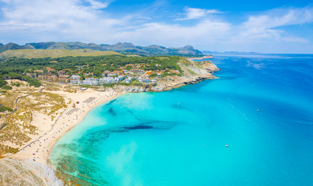 Stunning aerial view of Cala Mesquida, a pristine Mallorcan beach with turquoise waters, white sands, and a lush, protected natural landscape.の写真素材