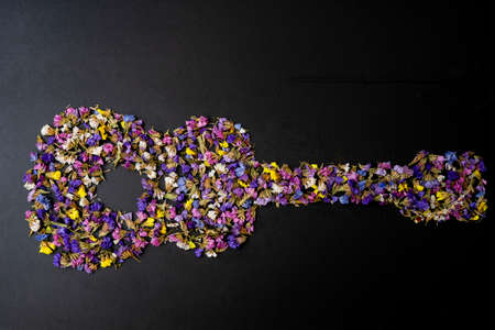 creative concept of a guitar made of limonium sinuatum flowers, isolated on black