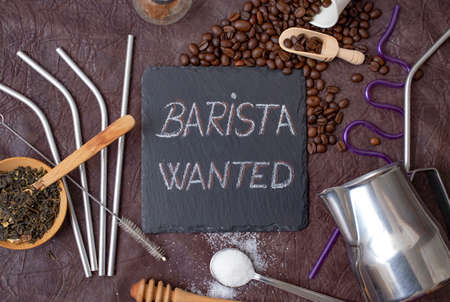 barista wanted written with chalk on a black stone tile, surrounded by coffee, tea, sugar and bartender utensilsの写真素材