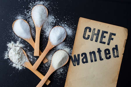 Chef wanted, written on vintage yellowed paper, next to 5 bamboo wooden teaspoons full of salt, sugar flour and  semolinaの写真素材