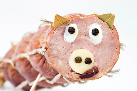 Selective focus photo of a funny pig's face made from a pork salami, cheese, bay leaves and black pepperの写真素材