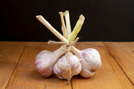 garlic bouquet on wooden boards table, and black backgroundの写真素材