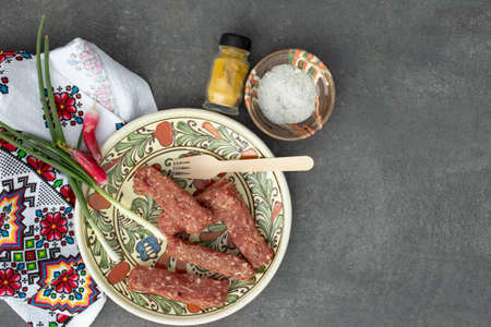 Mititei or mici on a plate, ready for grill on a grey tile backgroundの写真素材