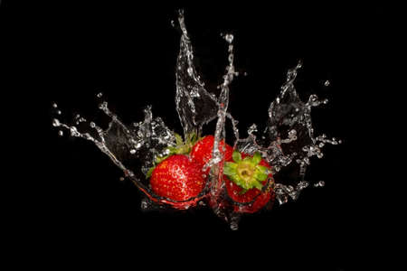 three strawberries with water splash on black background, movement blur water splashの写真素材