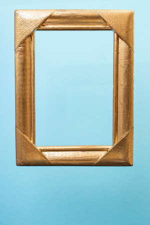 Golden empty frame levitating on light blue backgroundの写真素材