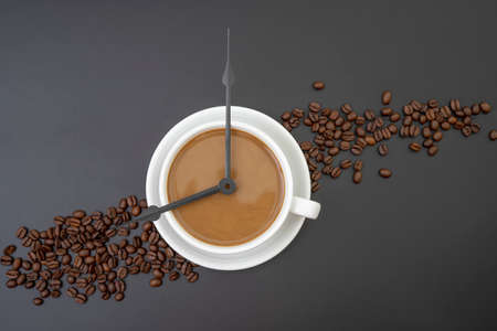 Coffee with milk and clock tongues showing 8 o`clock isolated on black.