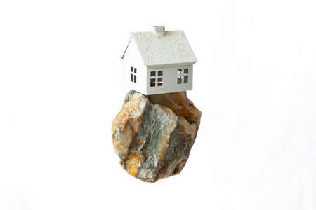 miniature model house levitating on a big rock, isolated on white backgroundの写真素材