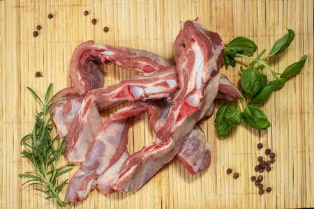 Raw beef ribs, on a bamboo placemat with fresh green basil and rosemaryの写真素材
