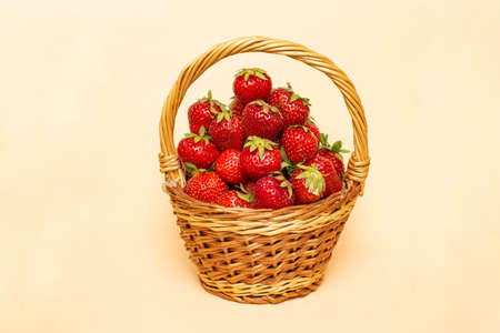 Basket full of strawberries isolated on beige background.の写真素材