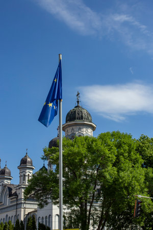 Radauti, Romania - 05 27 2022: European Union flag with an orthodox cathedral and trees in the backgroundのeditorial素材