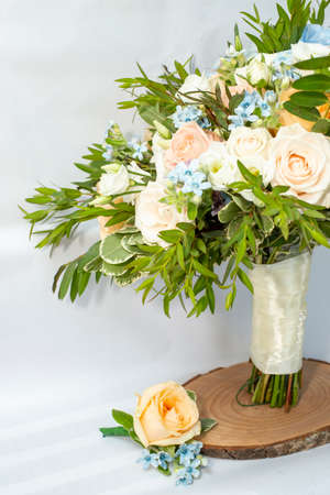 Brides bouquet and matching suit boutonniere with roses and small blue flowers, cropped view with...