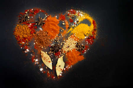Multiple various spices forming a heart shape, isolated on black background.の写真素材