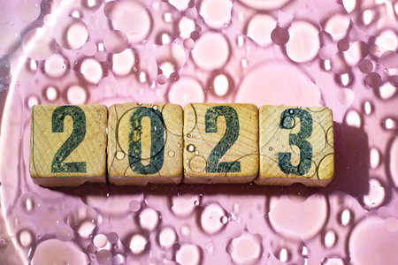 2023 number written on wood cubes, with oil circles shadows, abstract happy new year background.