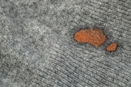 Dried red tomato stain on cashmere fabric, soft focus close up