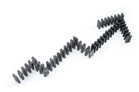 Ascending graph arrow, made from black domino tiles on white background, soft focus close up