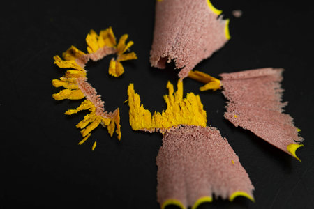 Waste from Sharpening a yellow colored crayon on black background, soft focus macro