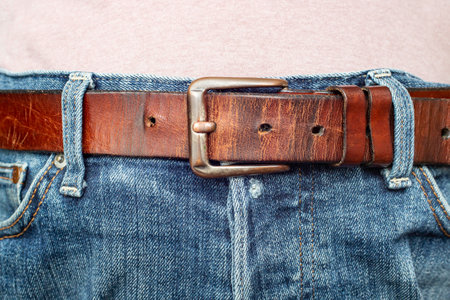 Thick brown belt on worn blue jeans, soft focus close upの写真素材