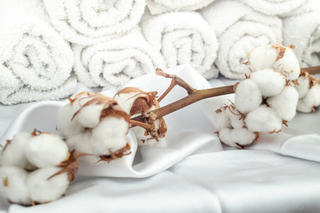 Cotton buds on white satin and rolled towels in the background, soft focus close upの写真素材