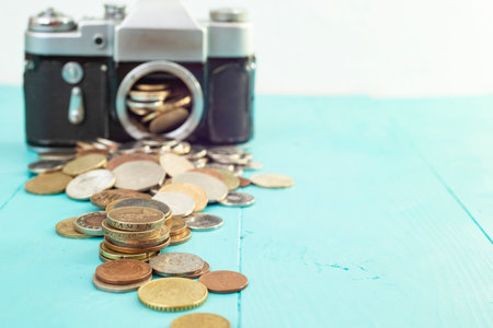 Defocused vintage camera with coins on the foreground, on blue background, soft focus close upの写真素材