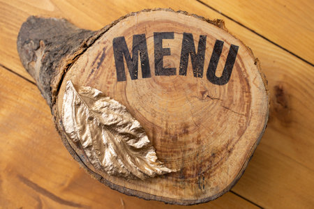 menu written on a slice of wood , with a golden leaf, restaurant menu cover mockupの写真素材