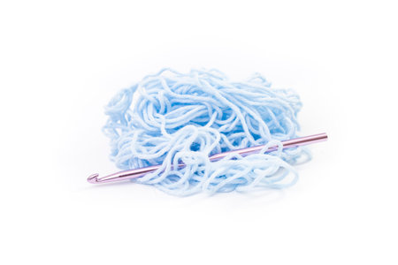 Bright blue tangled thread with a purple colored crochet hook, close up isolated on whiteの写真素材