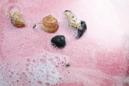 White foam, water and pink glitter with sea shells, abstract sea shore backdrop, soft focus close upの写真素材