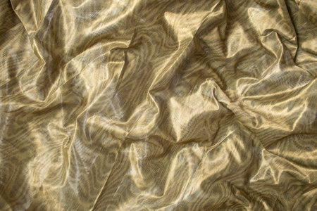 Metallic green fabric with shiny folds, soft focus backdropの写真素材