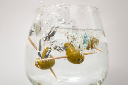 Green olive splash in a glass on white background, soft focus close up with motion blurの写真素材