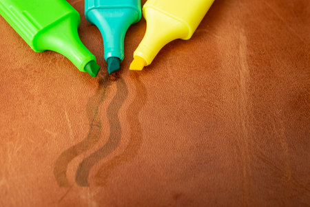 Permanent green, blue and yellow  markers scribbling on red brown leather,  soft focus close upの写真素材