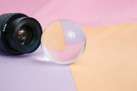 Generic macro camera lens model shooting thru a lens glass ball, on beige and pink colors, abstract...